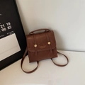 Sac à dos vintage marron foncé en similicuir avec boucle dorée dans un décor minimaliste - Marron