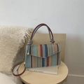 Colorful woven crossbody bag with striped pattern and gold hardware on a wooden stool - Blue