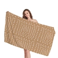 Thick beach towel with brown geometric white polka dot pattern held by a model - Brown Irregular Polka Dot Decor (4)