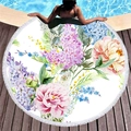 Thick round beach towel with vibrant floral print and white tassel trim on wood deck - Pink Peony Style
