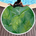 Circular beach towel with green palm leaf print and white fringe tassels on wood deck - Fresh Palm Leaves Style