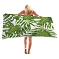 Tropical green plant leaf beach towel held by a model showcasing the full pattern - 150x75cm / Mixed Monstera and Palm (3)