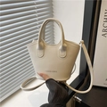 Cream vintage bucket bag with top handle and fashion logo in a minimalist interior setting - White