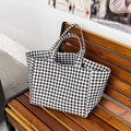Bolso tote de lona a cuadros blancos y negros sobre un banco de madera - Negro