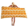 Thick orange beach towel with white sun and wave patterns shown by a female model - Bright Orange Sun Pattern (09)
