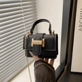 Classic black square mini handbag with gold metal clasp and chain strap in hand - Black