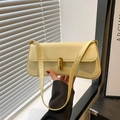 Bolso de hombro minimalista de cuero amarillo crema con cierre dorado mostrado de mano - Amarillo
