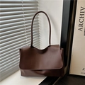Bolso de hombro minimalista de cuero marrón oscuro con solapa en un ambiente moderno - Marrón