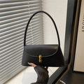 Primer plano del bolso baguette vintage negro con hebilla dorada y textura de cuero mate - Negro