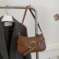 Vintage brown baguette bag with golden bow hardware on a dark grey suit background - Brown