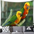 Wall tapestry featuring two vivid parrots on branches above a modern sofa backdrop - Sun Parakeets Style