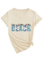 Dettaglio della t-shirt beige con scollo a V, stampa BEACH e nodo alla moda in vita - S / Sabbia