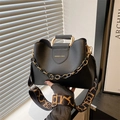 Black bucket bag with gold handle, chain decor and patterned strap in urban setting - Black