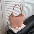 Borsa a secchiello rosa minimalista con dettagli dorati su sfondo di un libro - Rosa Senza Pendente