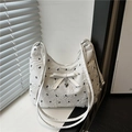 White quilted crossbody bag featuring a delicate bow and silver heart pendant detail - White