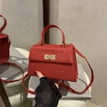 Rode glitter crossbodytas met gouden draaisluiting getoond vanuit een handperspectief - Rood
