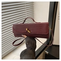 Détail du sac baguette bordeaux motif crocodile avec un fermoir rotatif en métal doré - Rouge