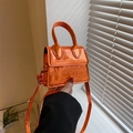 Mini oranje handtas met krokodillenleer textuur en handvat in de hand vastgehouden tas - Oranje