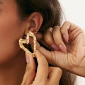 Golden irregular heart earrings with textured wrinkle design shown on a model - Gold Heart Crumpled Style (03642)