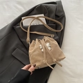 Beige drawstring bucket bag with silver bow accent and adjustable strap on a blazer - Khaki
