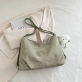 Sage green tote bag with cloud texture and white plush charm on beige blazer - Green