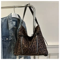 Macro shot of leopard print tote bag detailing with silver zippers and decorative drawstring - Brown