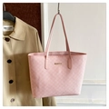 Dettaglio della borsa tote rosa con logo dorato e tracolla lunga su parete bianca - Rosa