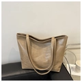 Dettaglio della grande borsa tote kaki in PU con motivo a rilievo unico su un divano - Cachi