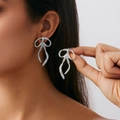 Close-up of oversized silver irregular ribbon earrings on model showing modern metallic texture - Long Bow Tassel (3699) / Gold (3699)