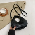 Elegante borsa a mezzaluna nera con trama intrecciata e zip dorata su un blazer beige - Nero
