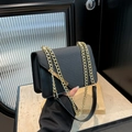 Elegant black shoulder bag with gold chain strap and textured flap in lifestyle setting - Black
