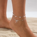 Close-up of double-layer ankle bracelet with faux pearls and bow pendant on sand - Bowknot Artificial Pearl Style (06392) / Silver