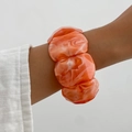 Detail eines Armreifs aus marmoriertem Harz mit geometrischen Facetten am Handgelenk - Marmormuster Orange (0120)