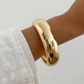 Detailansicht eines breiten goldenen Armreifs mit hochglanzpolierter Oberfläche am Handgelenk - Glänzendes Gold (02662)