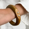 Dettaglio di un ampio bracciale in legno marrone caramello con rivetti in argento - Stile Marrone con Borchie (0111)