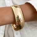Dettaglio di un ampio bracciale in metallo dorato con trama a coccodrillo e lucido - Oro Motivo Cocodrillo (02366)