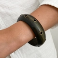 Detail van een brede harsarmband met metalen klinknagels gedragen om de pols - Donkerbruine Metalen Ring Decor Stijl (0110)