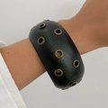 Detail view of a wide matte black cuff bracelet with decorative brass metal eyelets - Black (0113)