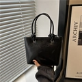 Bolso cubo minimalista negro brillante con asas anudadas y textura de piel plisada - Negro