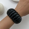 Close-up of a wide black acrylic bangle with a chunky marble-like rippled texture - Black