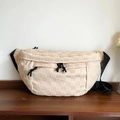 Borsa a tracolla intrecciata beige a scacchi con cinturino nero su superficie in legno - Bianco Sporco