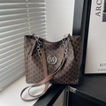 Brown monogram tote bag with M print and chain straps on a minimalist window sill - Brown