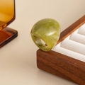 Detail shot of chunky olive green marble resin ring on a wooden jewelry display - Green-00940