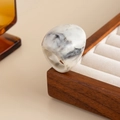 Close-up of a thick resin ring with black and white ink marble texture on a wood display - White Gray-00940