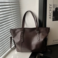 Borsa tote marrone scuro con borchie a stella e tracolla in un ambiente minimalista - Marrone