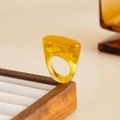 Detail of yellow amber resin ring with marble texture displayed on wooden stand - Light Coffee-00943