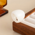 Macro detail of wide cream resin ring on wooden jewelry box showing polished texture - Off White