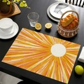 Detail van linnen placemat met oranje zonpatroon op een donkere houten tafel in de keuken - Stralende Zon
