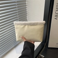 Pochette minimaliste en daim crème avec bordure en fausse fourrure blanche tenue à la main - Blanc