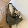Bolso hobo de ante gris oscuro con colgante de oso sobre un sofá blanco - Sin Colgante / Verde